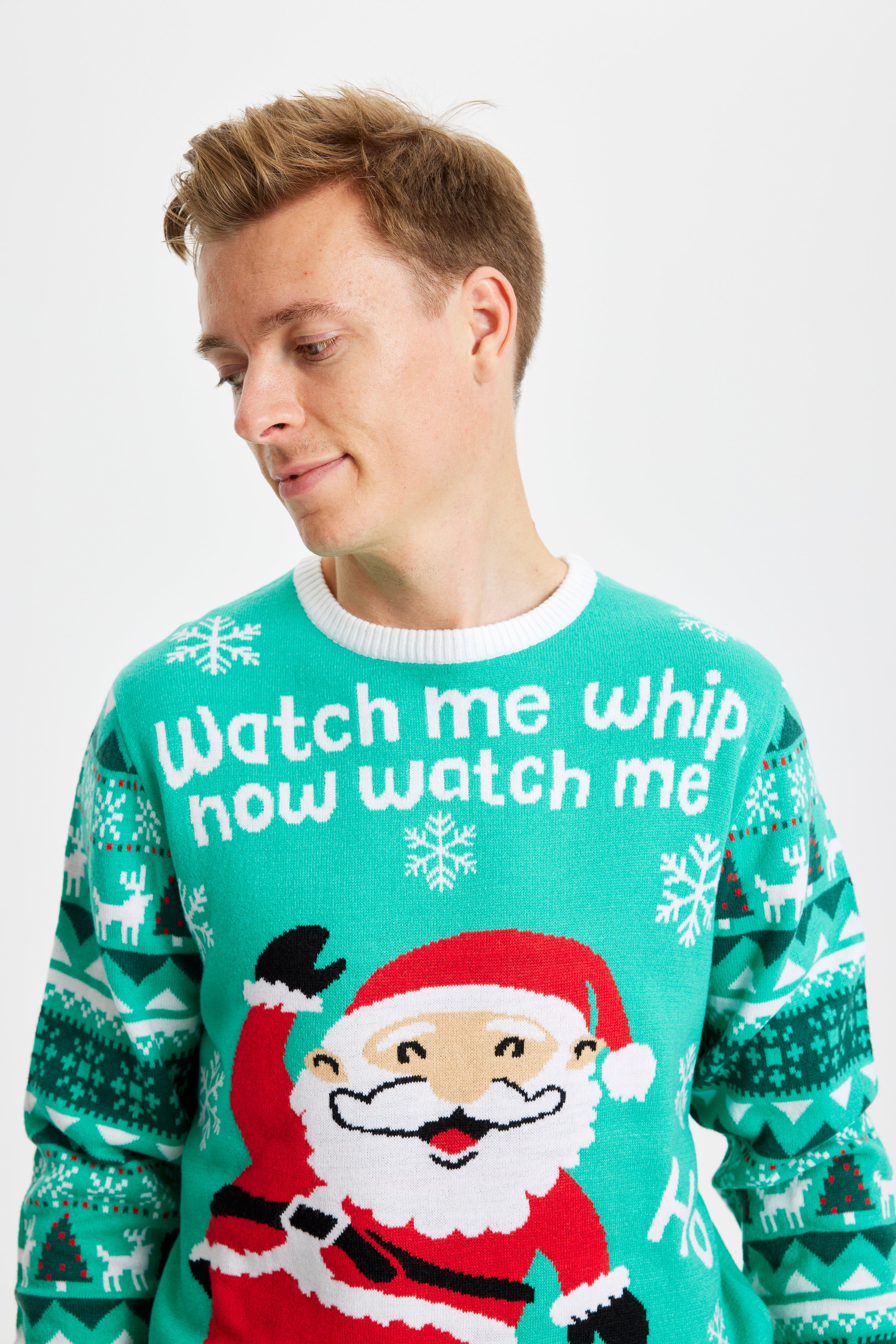 En mand der kigger ned er iklædt en turkis julesweater.